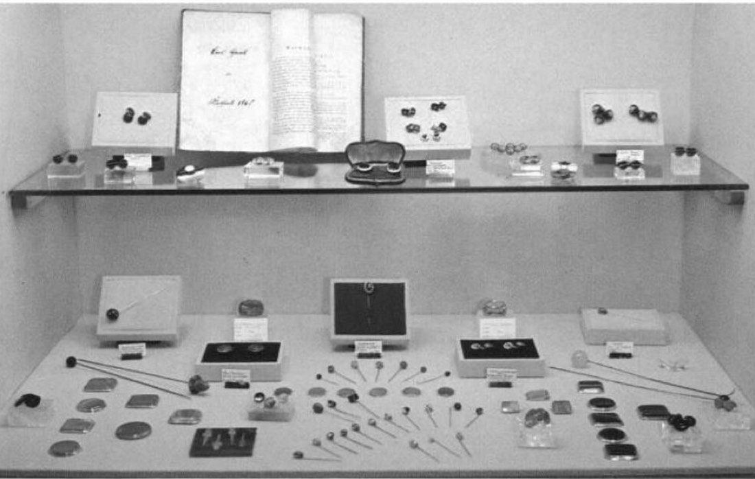 Vitrine mit geschliffenen Manschettenknopfteilen, Knopfsteinen und langen Haarnadeln